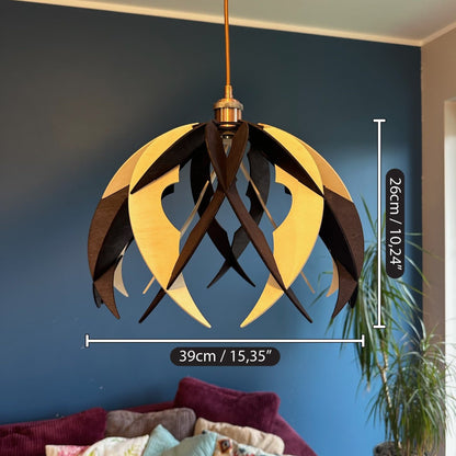 A wooden pendant light with pointed, curved ribs and circular cutouts, displayed in a living room setting. The image includes dimensions, showing the lamp's width (39 cm/15.35”) and height (26 cm/10.24”) to help visualize its scale in a space.