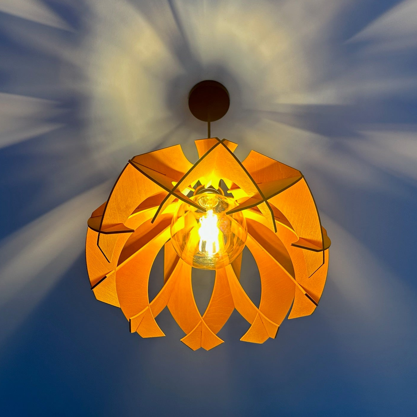 Modern wooden pendant lamp with a flower-like design, crafted from eco-friendly materials, casting beautiful light patterns on the ceiling.